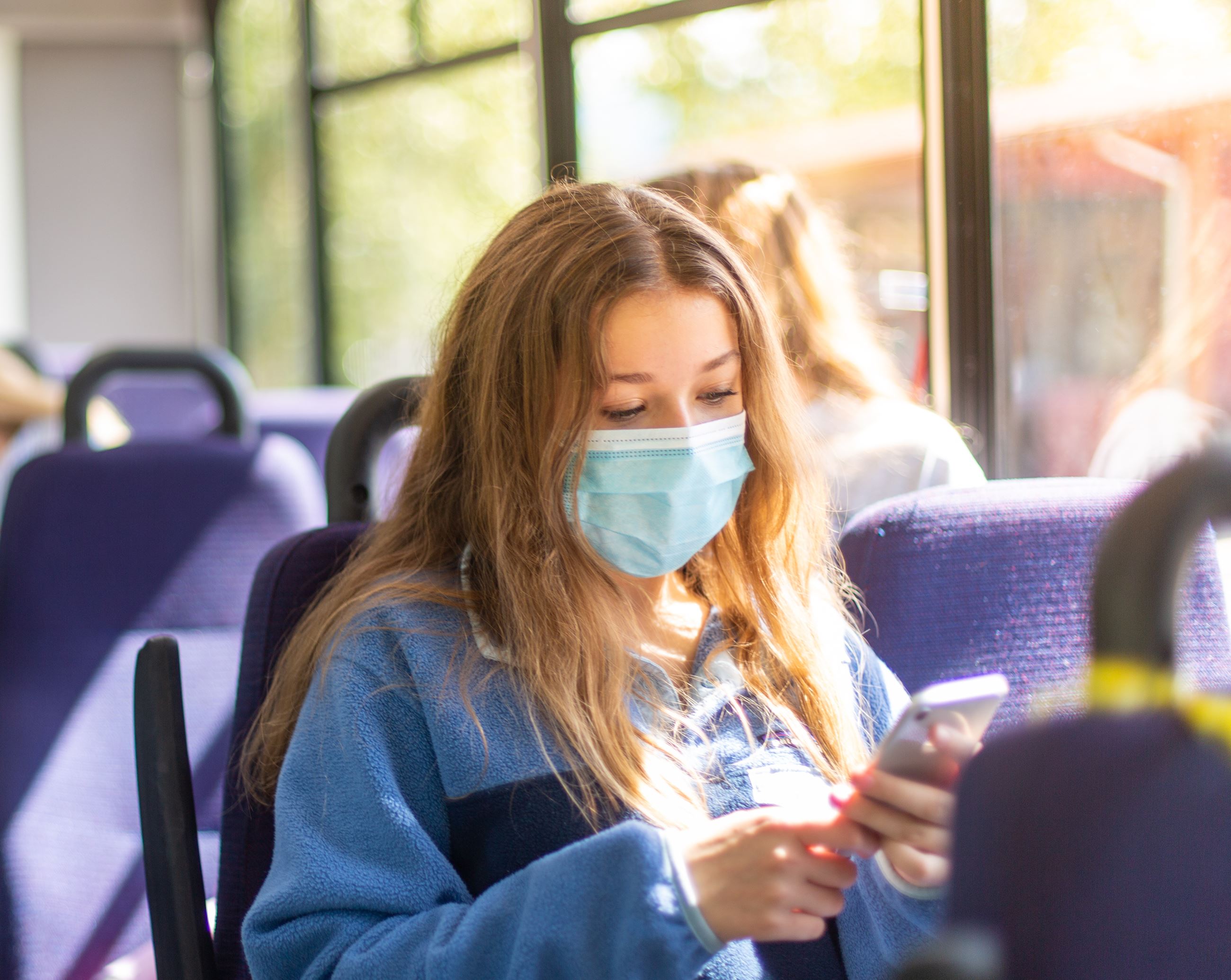 Young girl looking at phone on the bus