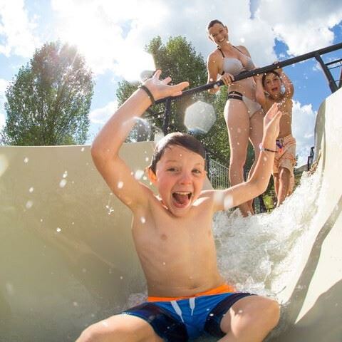 Kid riding down water slide, smiling